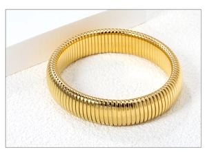 Dettaglio del bracciale rigido dorato in acciaio inossidabile con design a coste