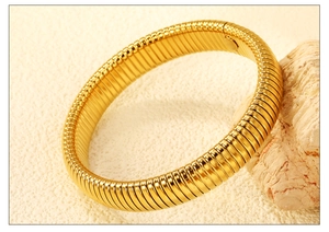 Macro di un bracciale flessibile Tubogas in acciaio inossidabile dorato su roccia bianca