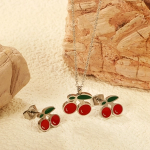 Gros plan d'un pendentif cerise et de boucles d'oreilles sur une surface de pierre