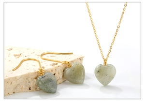 Detail view of heart-shaped natural stone necklace and matching earrings set in gold