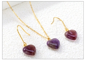 Macro shot of purple heart-shaped stone pendant and earrings set with gold chain