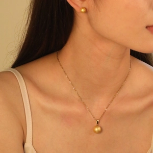 Parure de bijoux dorés avec collier à perle mate et boucles d'oreilles boules assorties