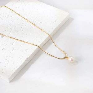 Minimalist gold beaded chain necklace featuring a single round freshwater pearl pendant