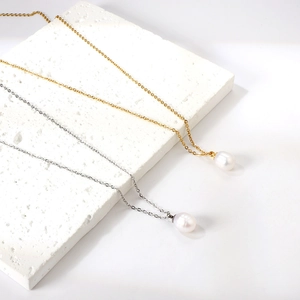 Elegant gold and silver stainless steel necklaces with freshwater pearl pendants on stone