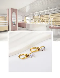 Détail de boucles d'oreilles créoles dorées avec pendentif poire en cristal