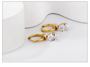 Gros plan de boucles d'oreilles créoles dorées avec pendentifs en zircon blanc en poire