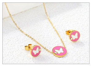 Detailed macro view of gold-plated butterfly necklace and stud earrings set with pink enamel