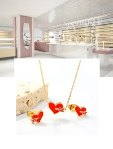 Macro view of gold stainless steel necklace and earrings set with red heart and arrow design