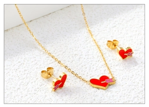 Detail of gold heart necklace and earrings set with red enamel and arrow design