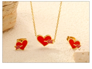 Close-up of golden Cupid's arrow and red heart jewelry set on a white stone base