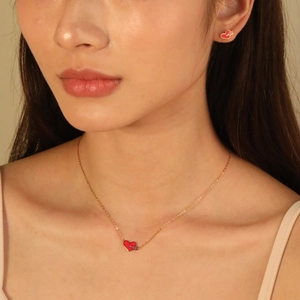 Golden necklace and heart earring set with red enamel cupid's arrow design on model