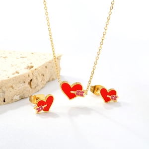Elegant gold heart jewelry set with red enamel pendants and arrow accents on stone
