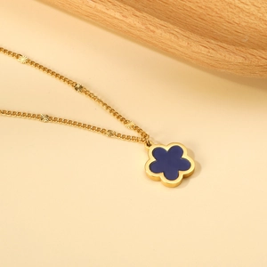 Dettaglio ravvicinato di una collana dorata con ciondolo a fiore blu e piccoli dischi di conchiglia