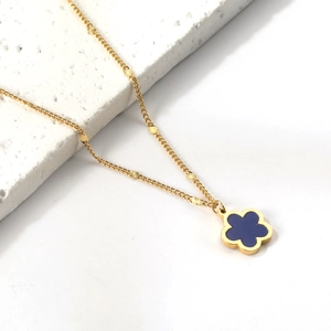 Dettaglio della collana dorata con ciondolo a fiore blu su base di marmo