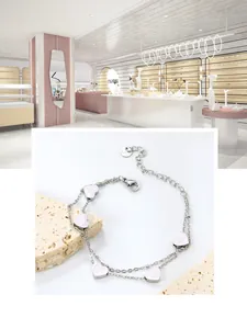 Detailed view of silver double-layered stainless steel bracelet with white heart charms