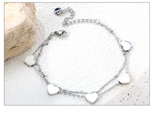 Detailed macro view of double-layer stainless steel bracelet with silver heart pendants