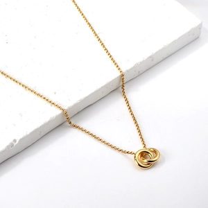 Collana minimalista in oro 18k con doppi anelli intrecciati su espositore in pietra bianca