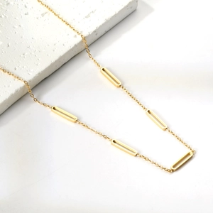 Collana minimalista placcata oro 18K con maglie geometriche su blocco di pietra bianca