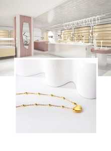 Détail du pendentif cœur et de la chaîne à billes dorées sur collier en acier inoxydable