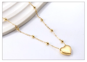 Gros plan d'un pendentif cœur plaqué or 18K avec chaîne à billes sur plateau blanc