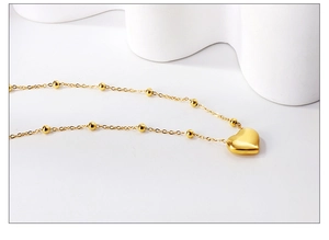 Gros plan détaillé du collier à pendentif cœur plaqué or 18 carats sur décor blanc épuré