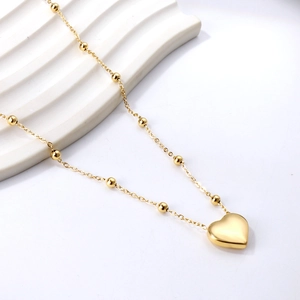 Collier avec pendentif cœur doré poli et chaîne à billes sur un support blanc élégant