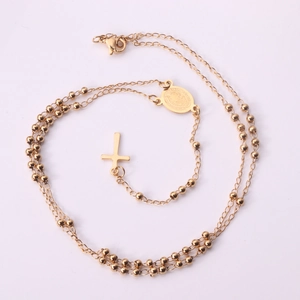 Gros plan sur collier chaîne à billes dorée avec médaille religieuse et pendentif croix
