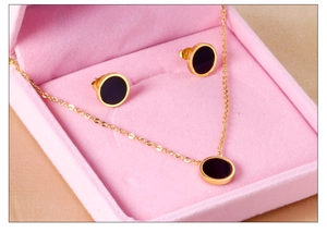 Macro view of gold stainless steel jewelry set with black shell round pendants