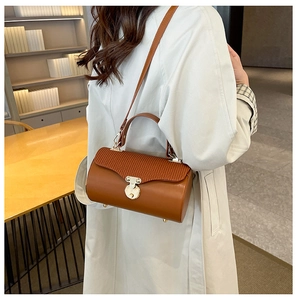 Detail of caramel leather box bag with pleated flap and gold round metal buckle