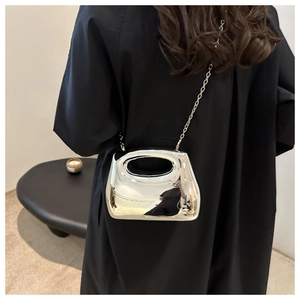 Macro shot of glossy silver mirror acrylic crossbody bag with metal chain strap detail