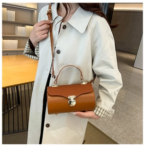 Detail of caramel box bag with pleated texture and golden circular metal lock clasp