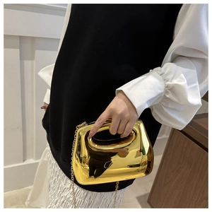 Elegant gold acrylic clutch bag with a mirror finish and thin chain strap worn by a model