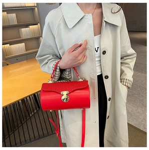 Detail view of red structured cylindrical box bag with wave pattern and gold metal lock