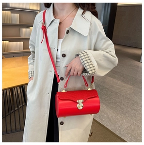 Chic red cylindrical box bag with wave pleated flap and gold buckle shown on model