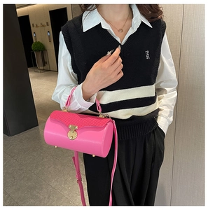 Detail of rose pink leather cylindrical crossbody bag with gold lock and textured flap