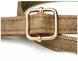 Close-up of adjustable tan twill shoulder strap with premium gold square metal buckle