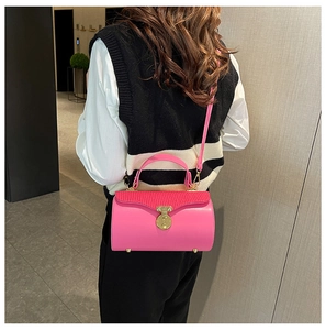 Detail of pink cylindrical handbag featuring red pleated lid and gold clasp on model