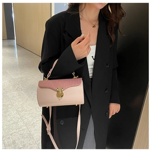 Detail of a pink cylindrical box bag with pleated flap and golden metallic closure