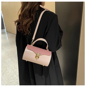 Detail of pink shoulder bag with striped texture flap and golden round lock on black coat