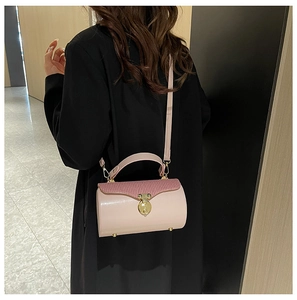 Detail of light pink cylindrical crossbody bag featuring purple pleated fabric and gold lock