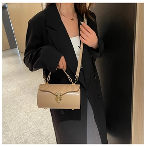 Detail view of cylinder shoulder bag with textured flap and elegant gold cylinder lock