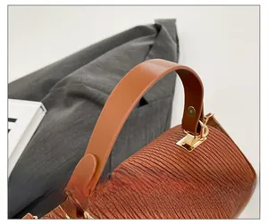 Detail of the pleated texture bag with leather handle and gold rivet hardware