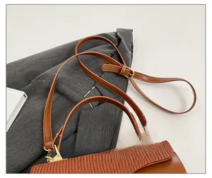 Detail of adjustable strap and golden hardware on brown pleated flap shoulder bag