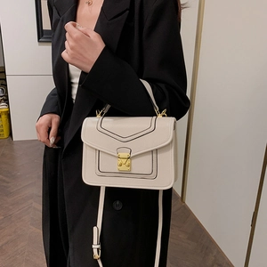 Chic ivory square handbag with gold lock hardware, shown on model in black blazer