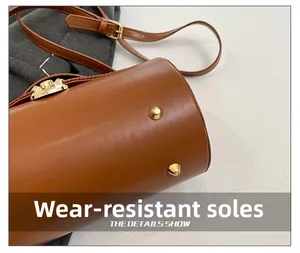 Detail view of brown leather bag with golden protective metal bottom studs and strap