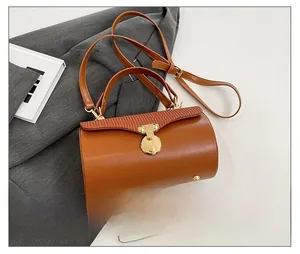Size comparison of a brown leather box bag with a smartphone and gold metal hardware