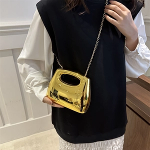 Glossy gold acrylic mini handbag with hollow handle and metallic chain strap
