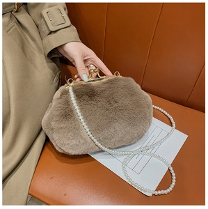Detailed view of plush brown faux fur shell bag with pearl strap and gold clasp on leather seat