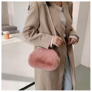 Close-up of a pink faux fur shell bag with elegant pearl strap on a stylish trench coat