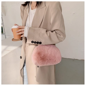 Close-up of a pink fuzzy plush shell bag styled with a pearl necklace and beige coat